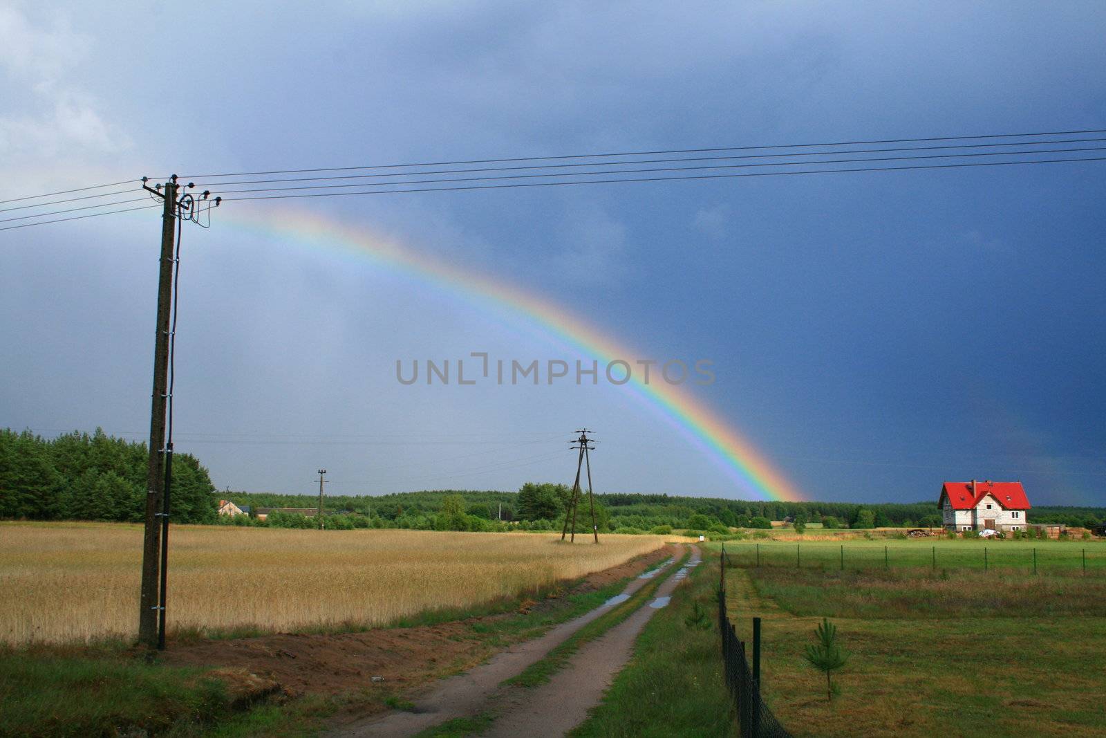 Rainbow after the storm with rural road and house
