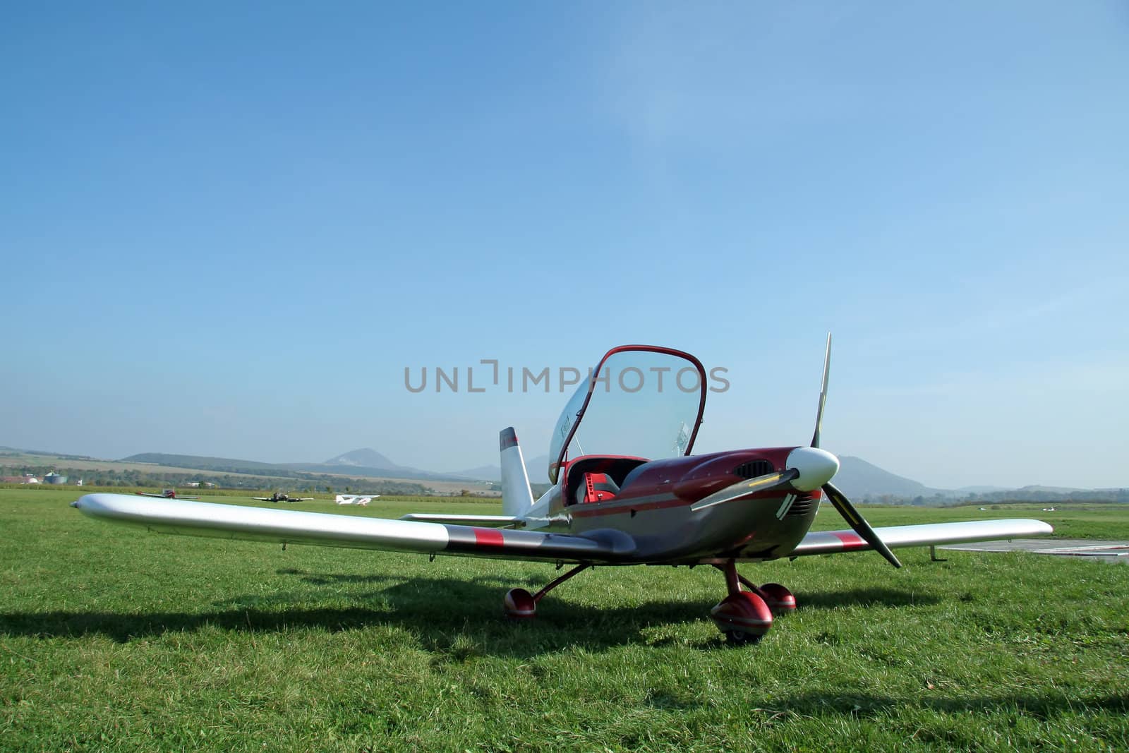 small private airplane, cockpit open, grass airfield