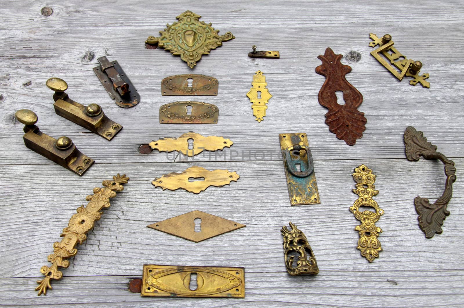 Many antique door locks and hardware designed for a weathered wooden board
 