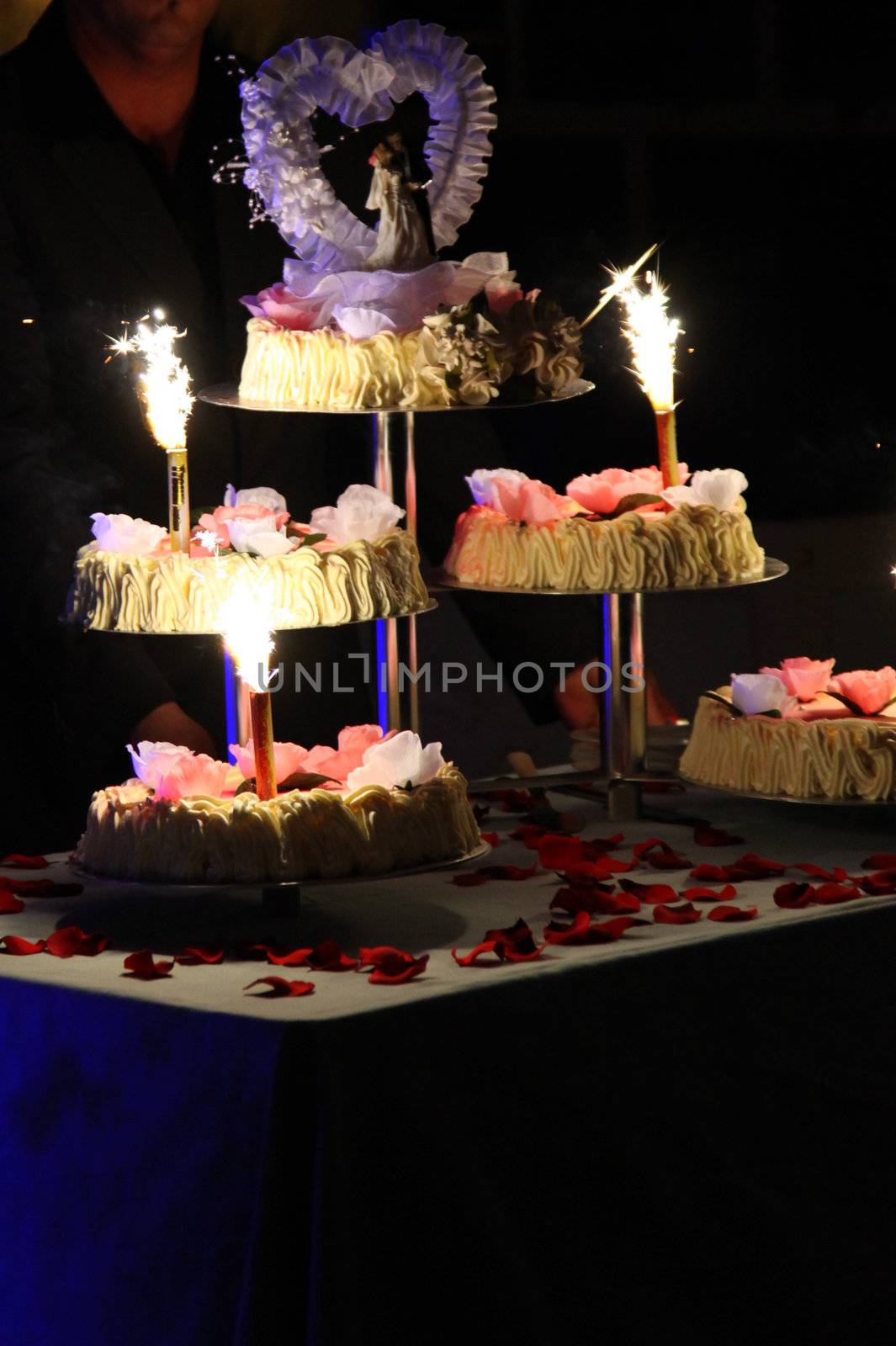tiered wedding cake with candles and fireworks on a table
