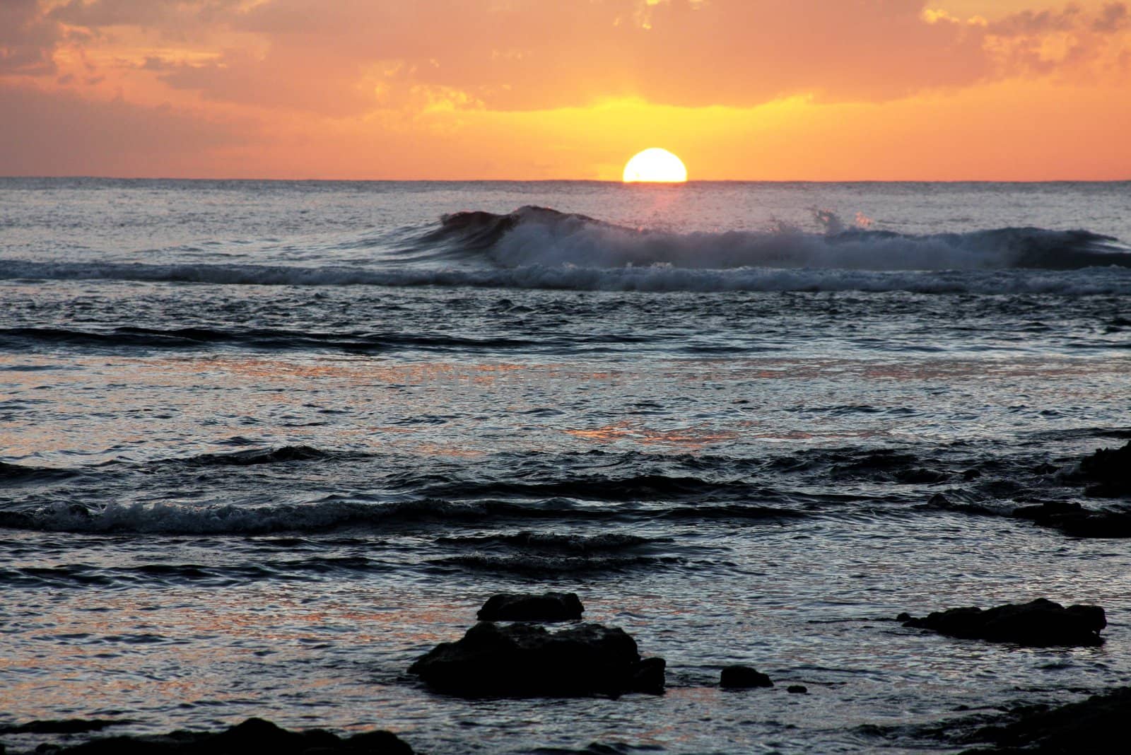 Reef surf at sunset with reflection and rocks