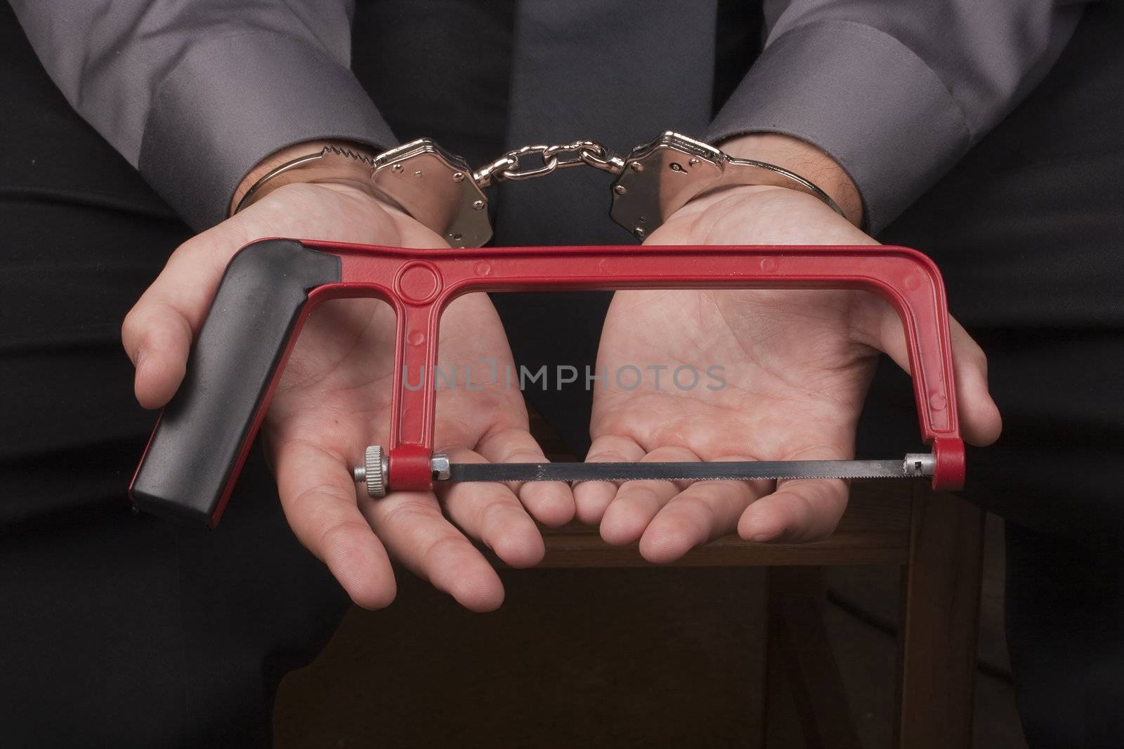 Arrested in handcuffs holding a hacksaw with a goal to remove the handcuffs.