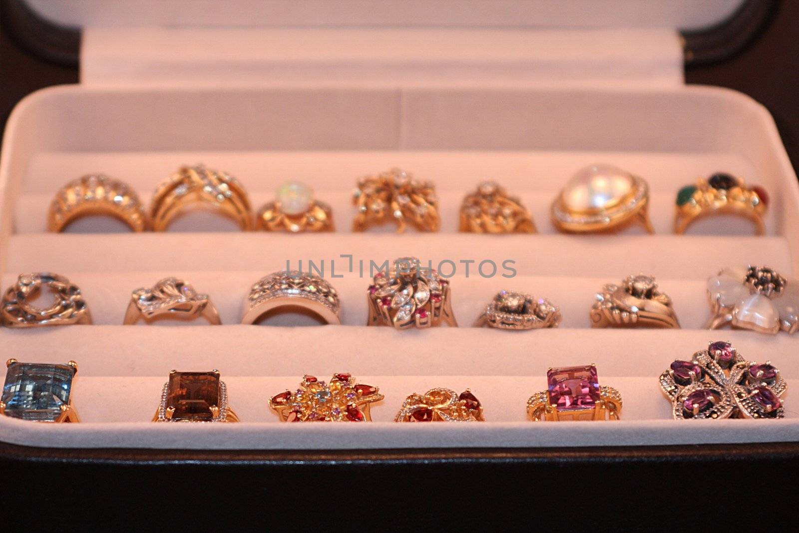 Open jewelry box with an assortment of diamond and gemstone gold rings.