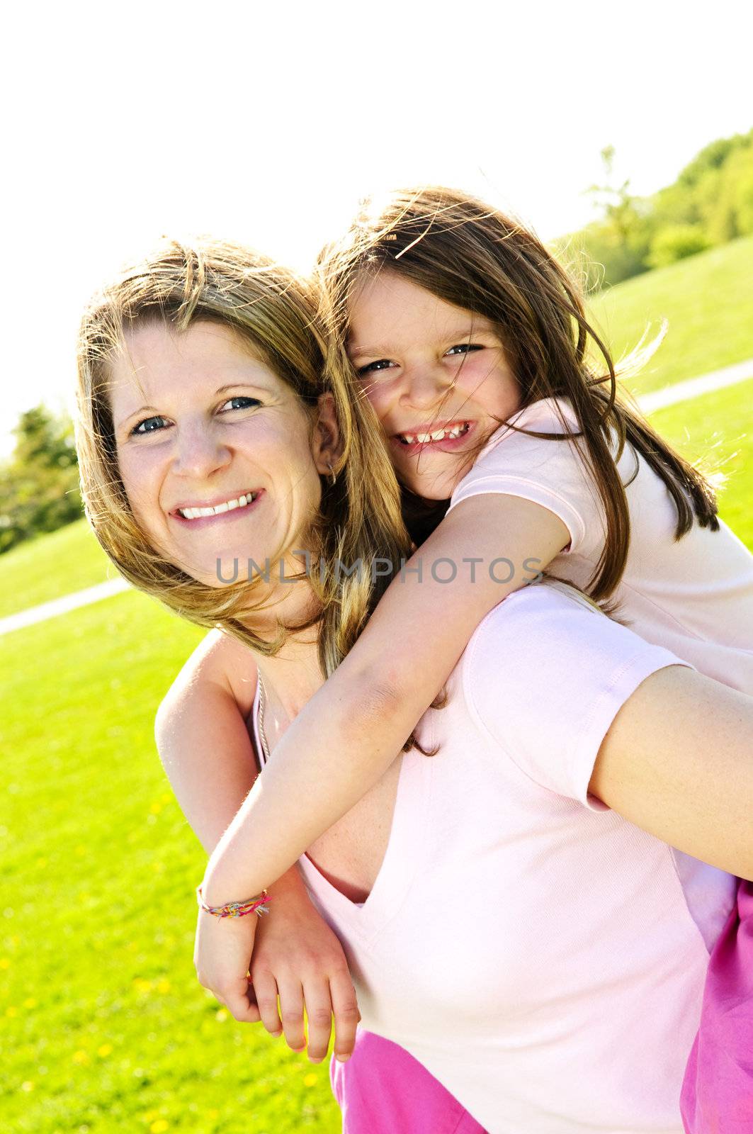 Portrait of happy mother giving piggyback ride to child