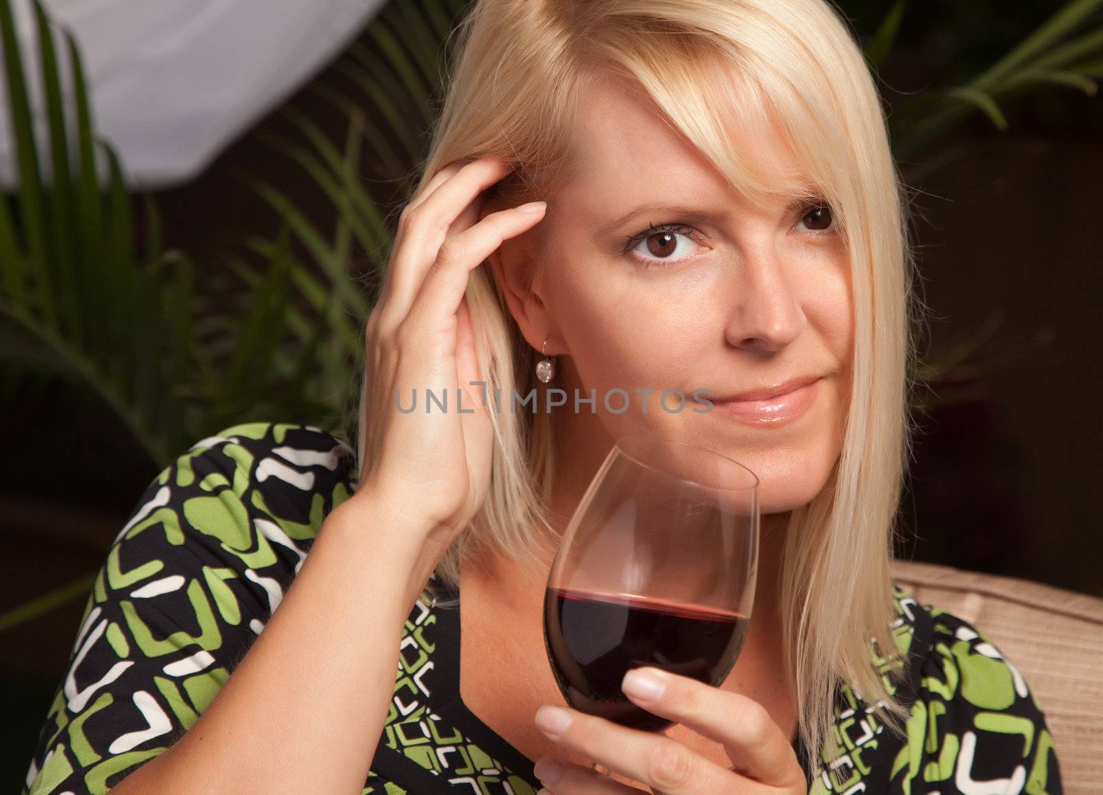 Beautiful Blonde Woman Smiling at an Evening Social Gathering Tasting Wine.