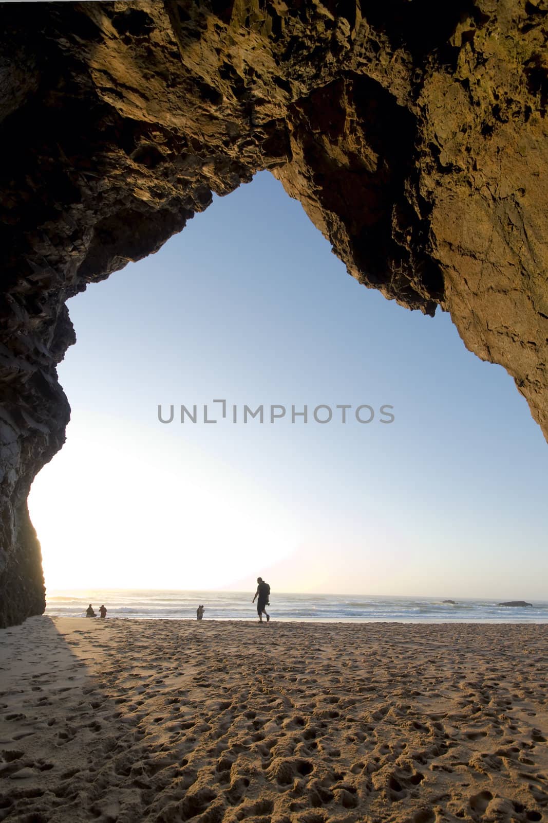 Tourist walking towards the, seen from a cave in the cliff