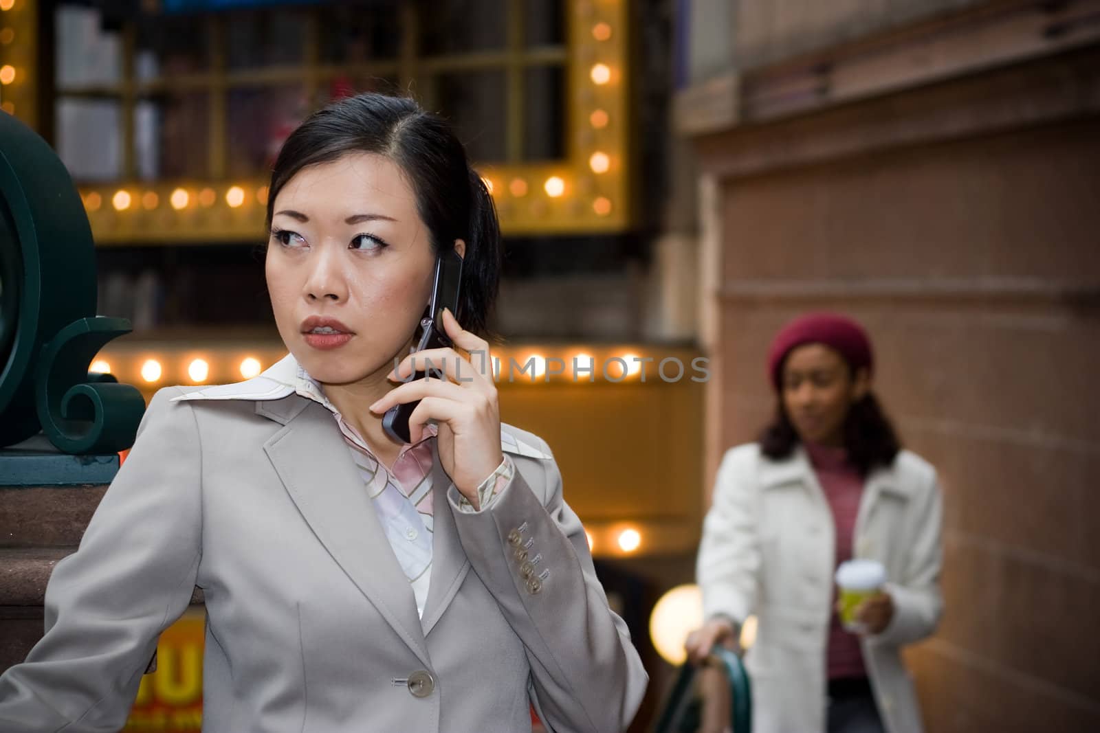 An attractive Asian business woman talking on her cell phone in the city.