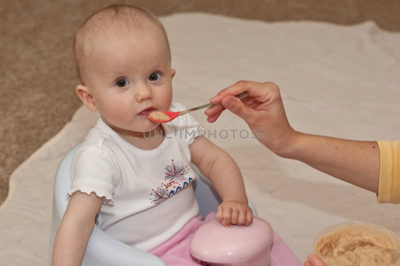 Mother is feeding little caucasian girl with oatmeal cereal.