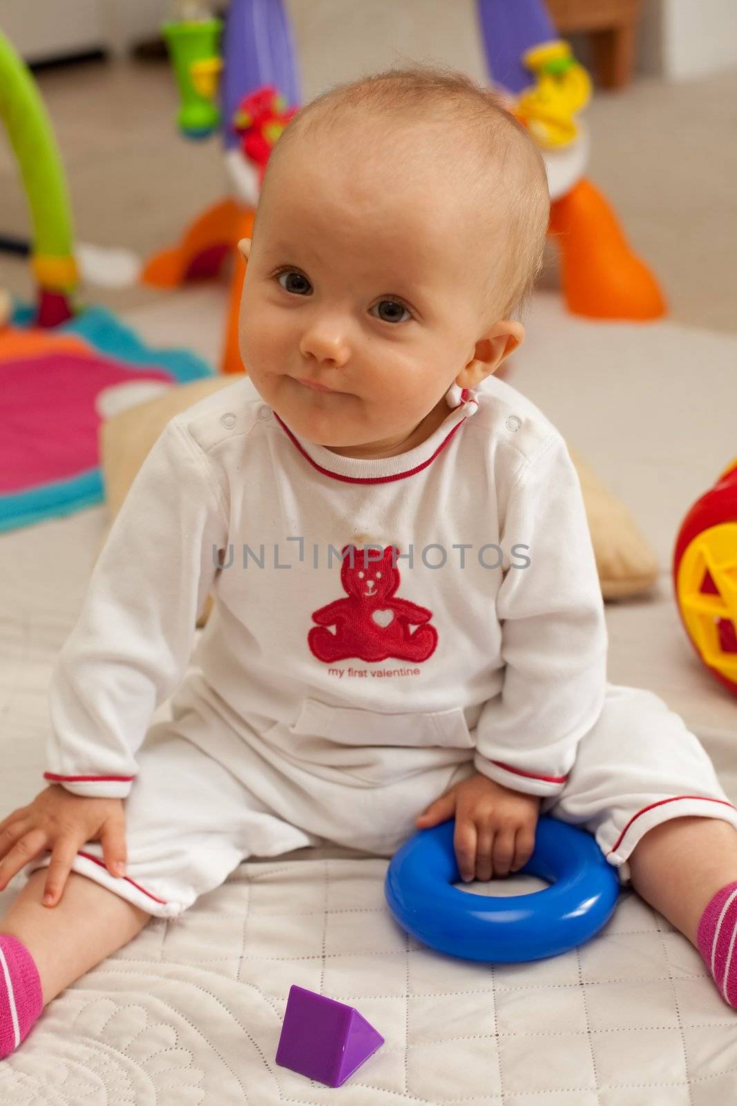 Caucasian baby girl playing on a floor.