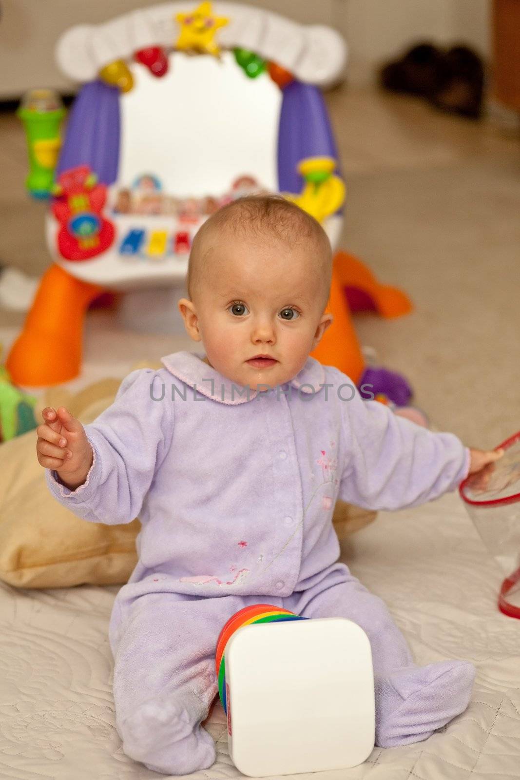 Caucasian baby girl playing on a floor.