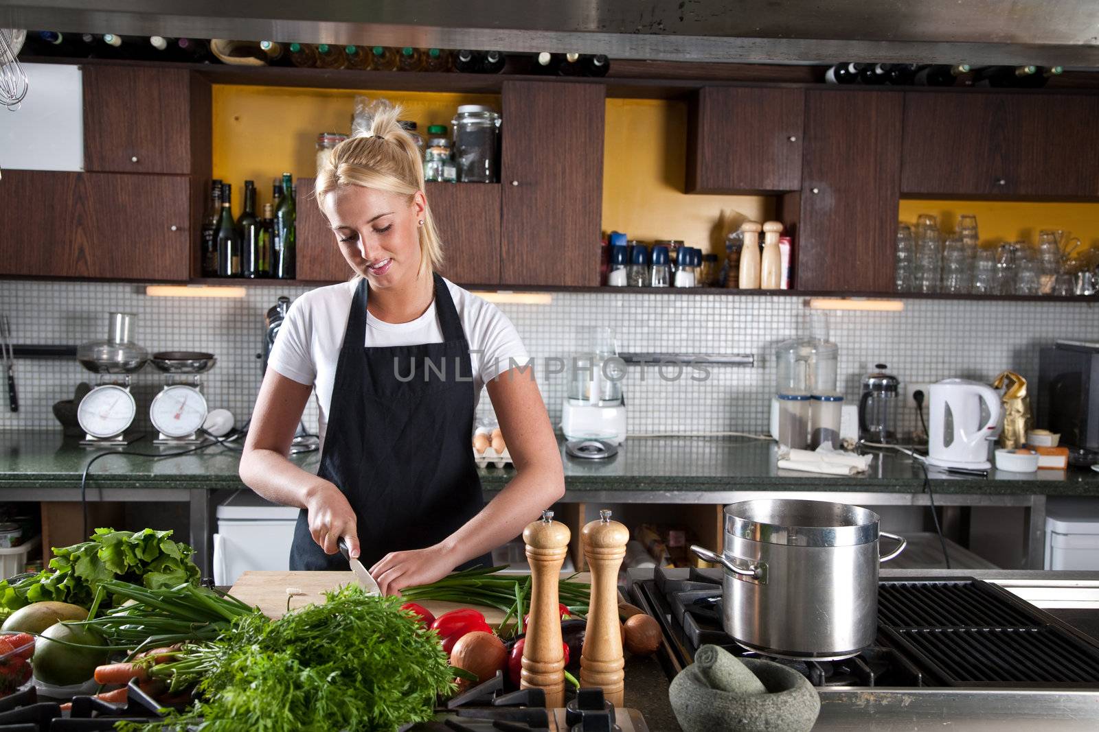 Pretty young blond woman working in a professional kitchen