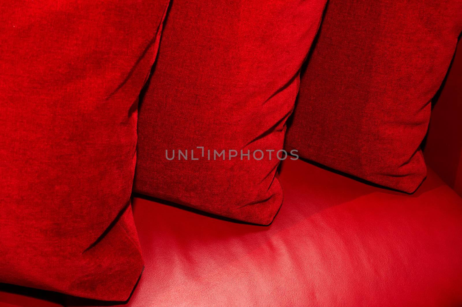 Three red pillows on a leather sofa