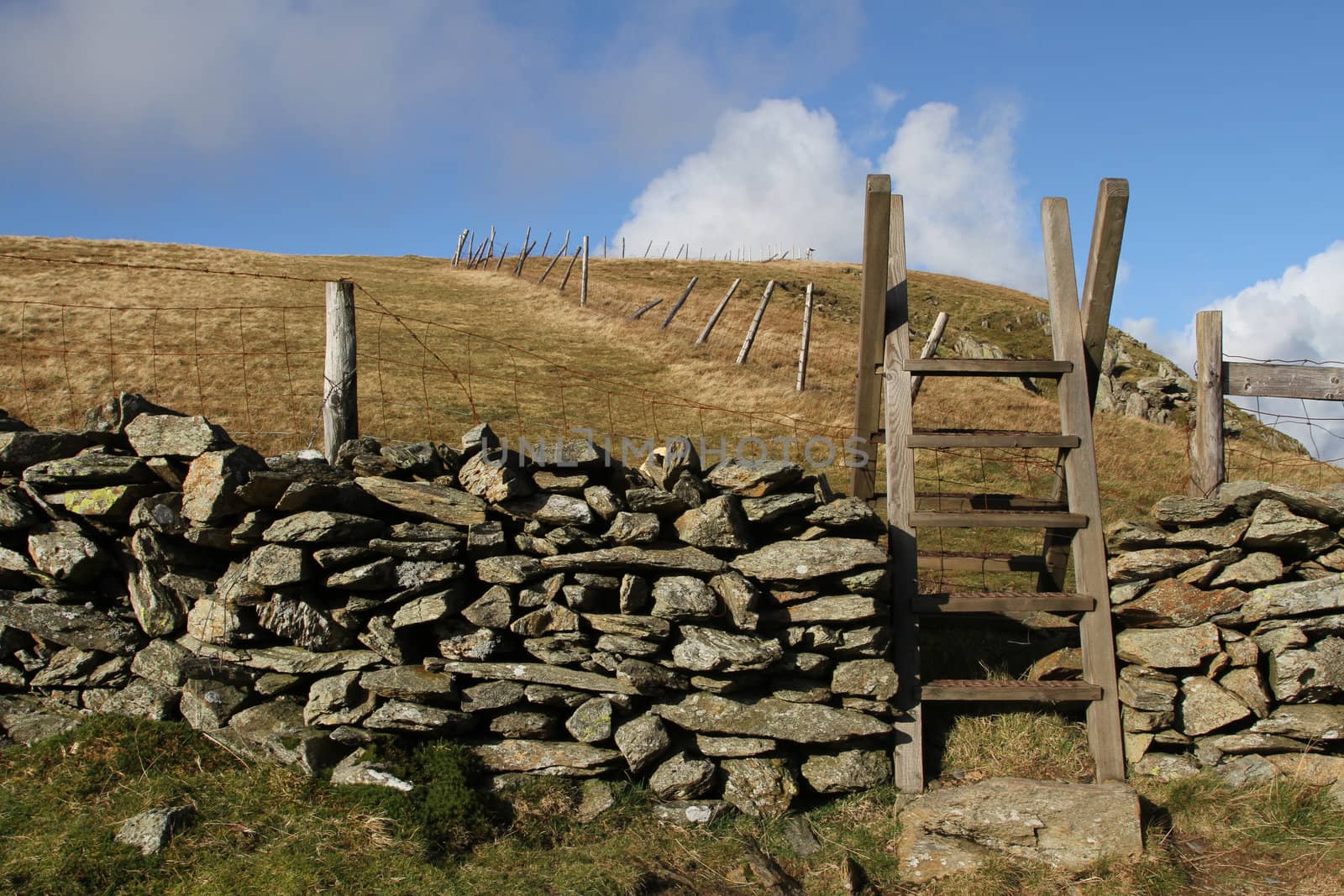 Wooden steps over a stone wall giving public access to national park land.