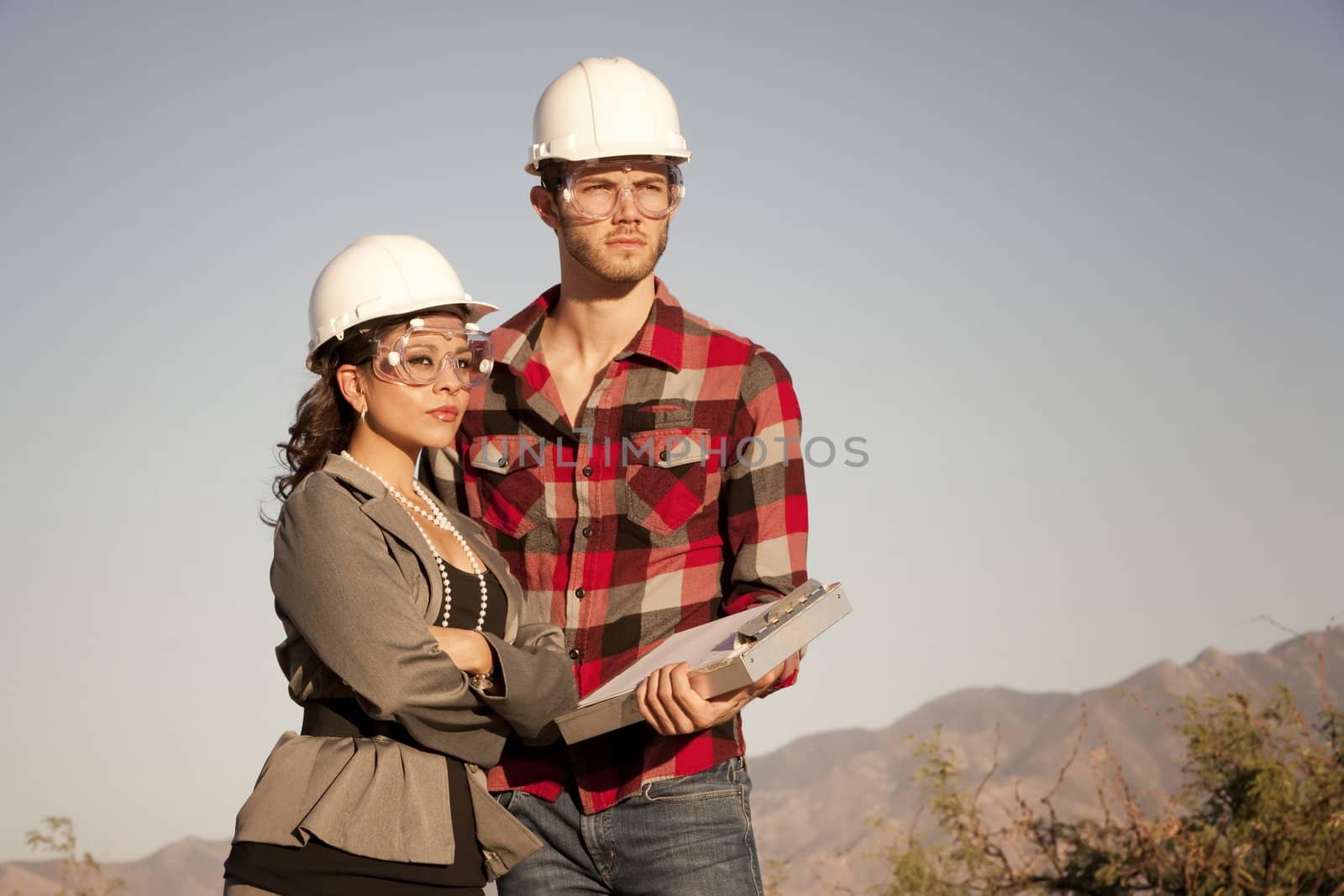 Handsome man and pretty woman outdoors wearing protective hardhats