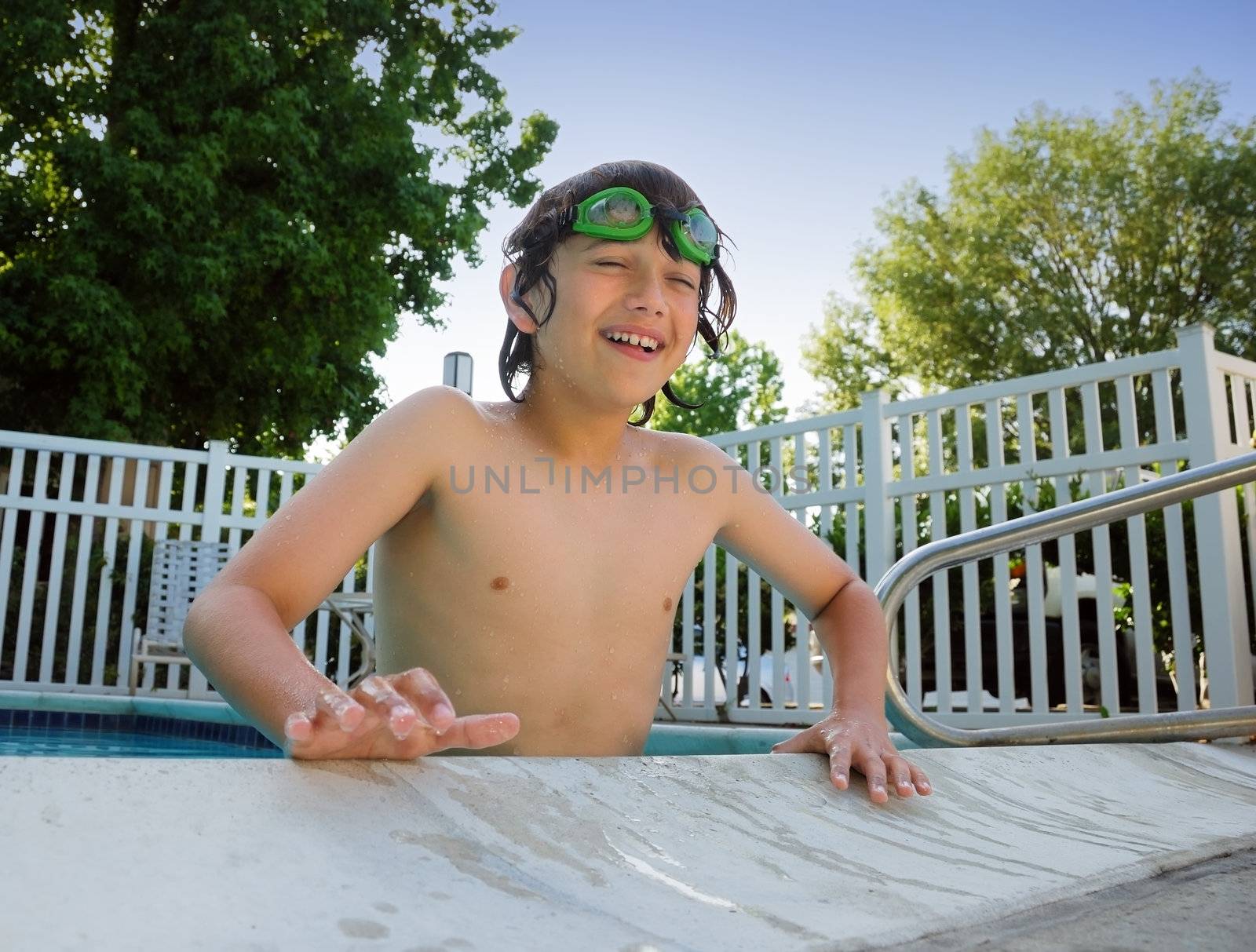 Teen boy with swimming goggles having fun at the pool.