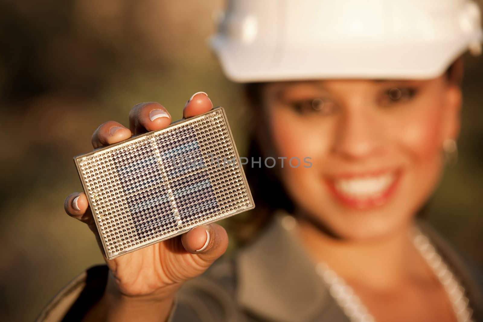 Pretty young woman wearing hardhat with small solar panel in hand
