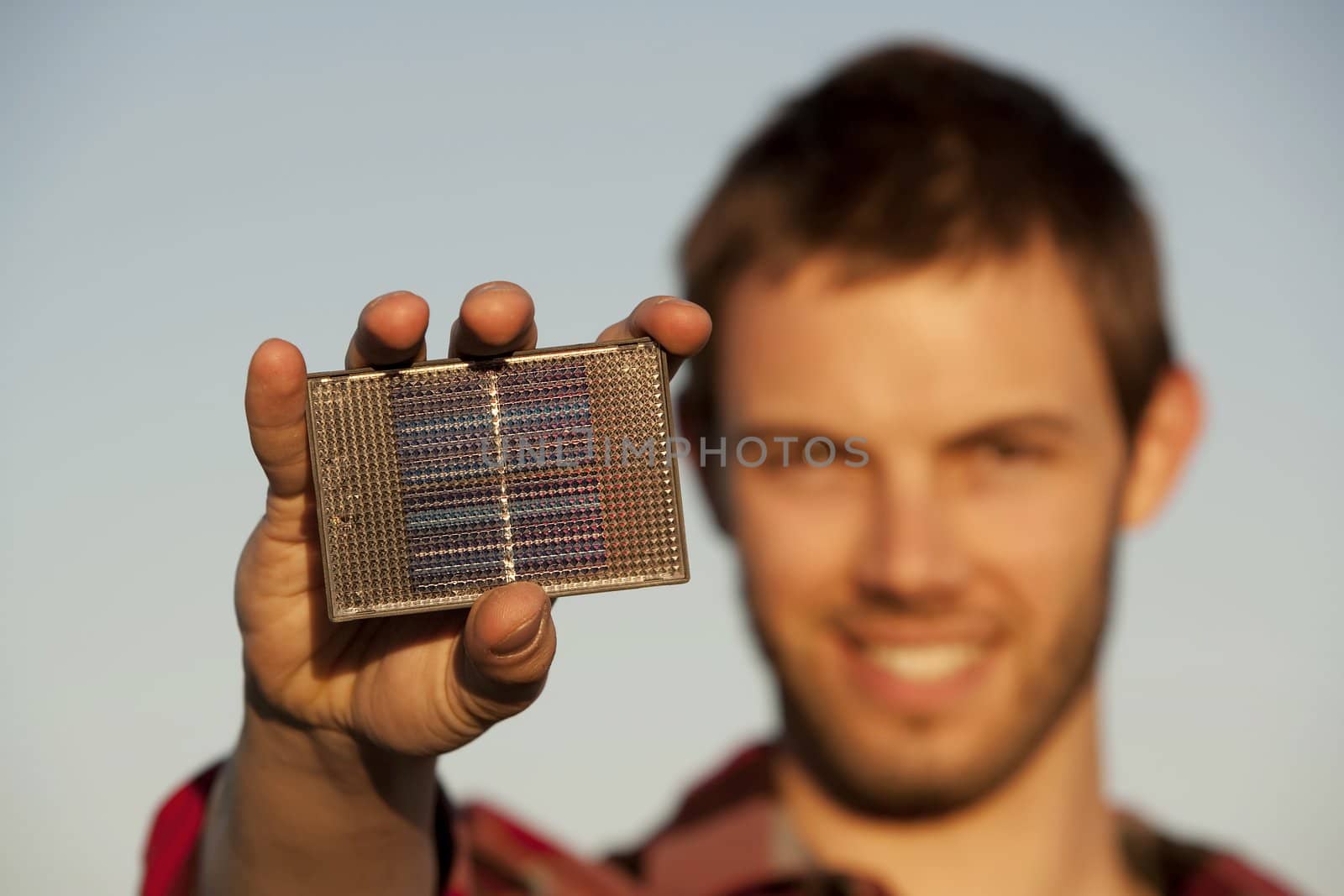 Handsome young man with small solar panel in hand