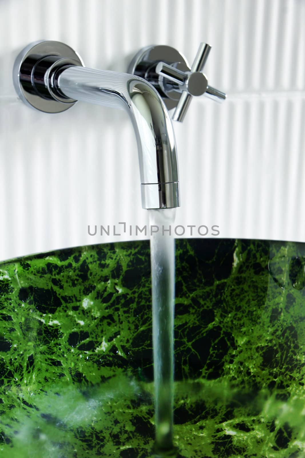 Contemporary bathroom: water running out of beautiful designer wall mounted faucet into tempered glass, fake green marble, vessel sink.