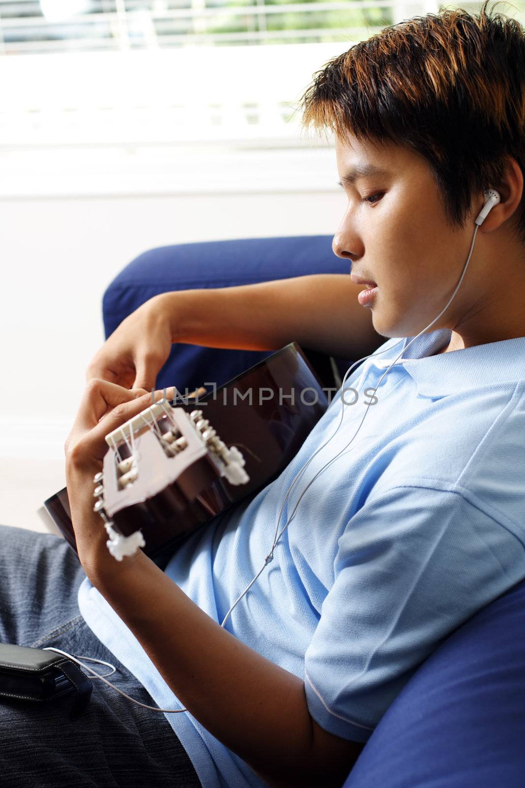 A man playing a guitar while listening to music