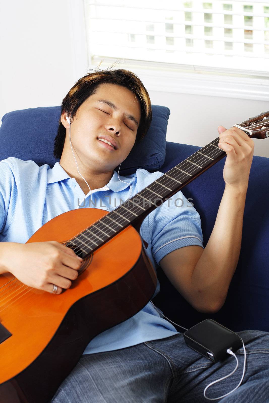 Young man relaxing at home by playing guitar