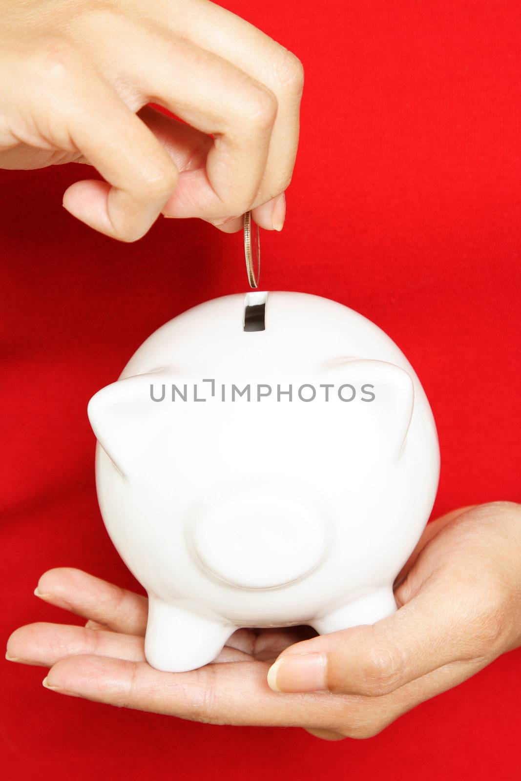 A woman depositing coin in a piggy bank