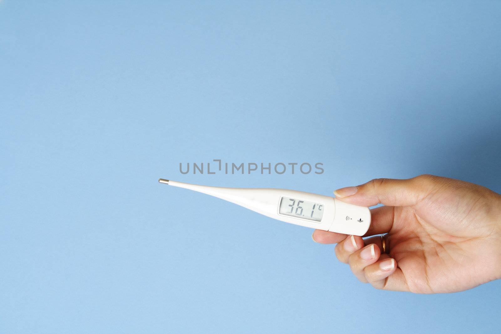 A woman's hand holding a digital body thermometer