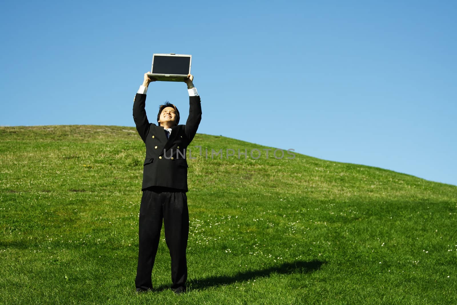 Happy businessman holding laptop high in the air