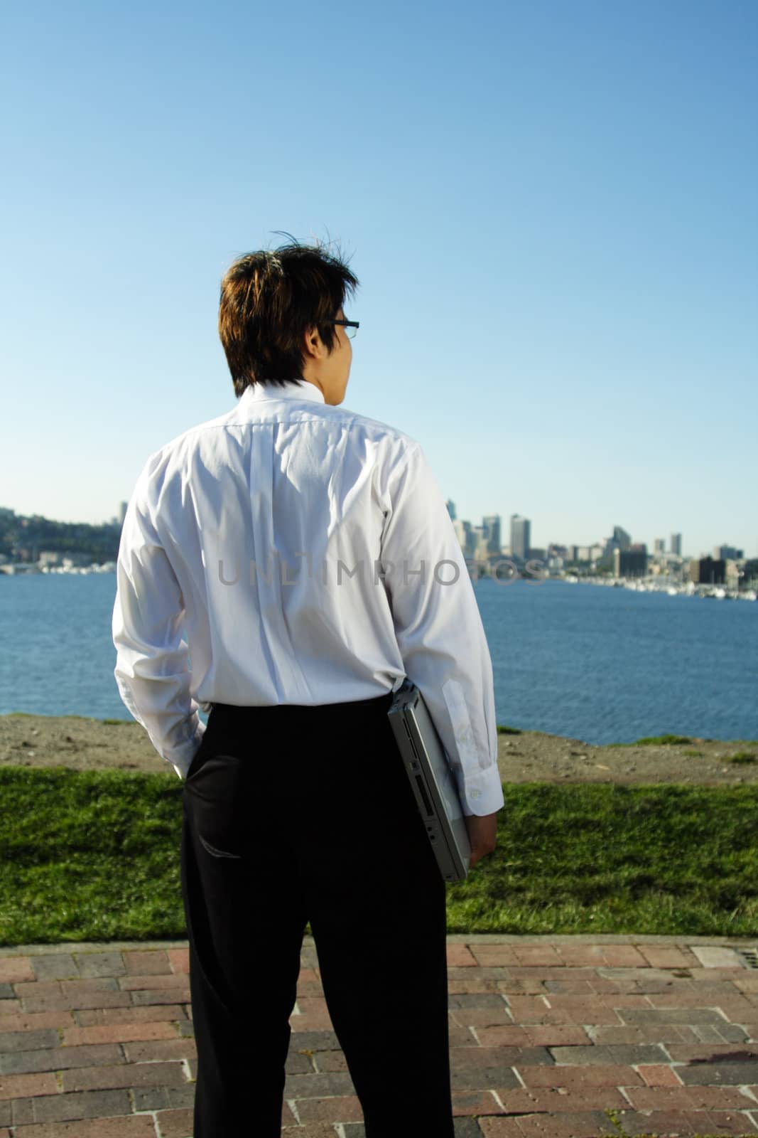 A businessman carrying a laptop relaxing at a park