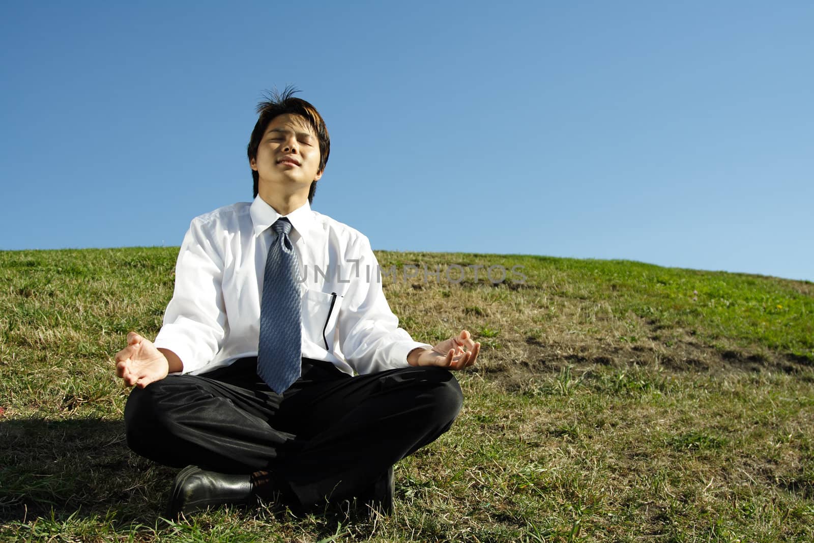 A businessman meditating in a park