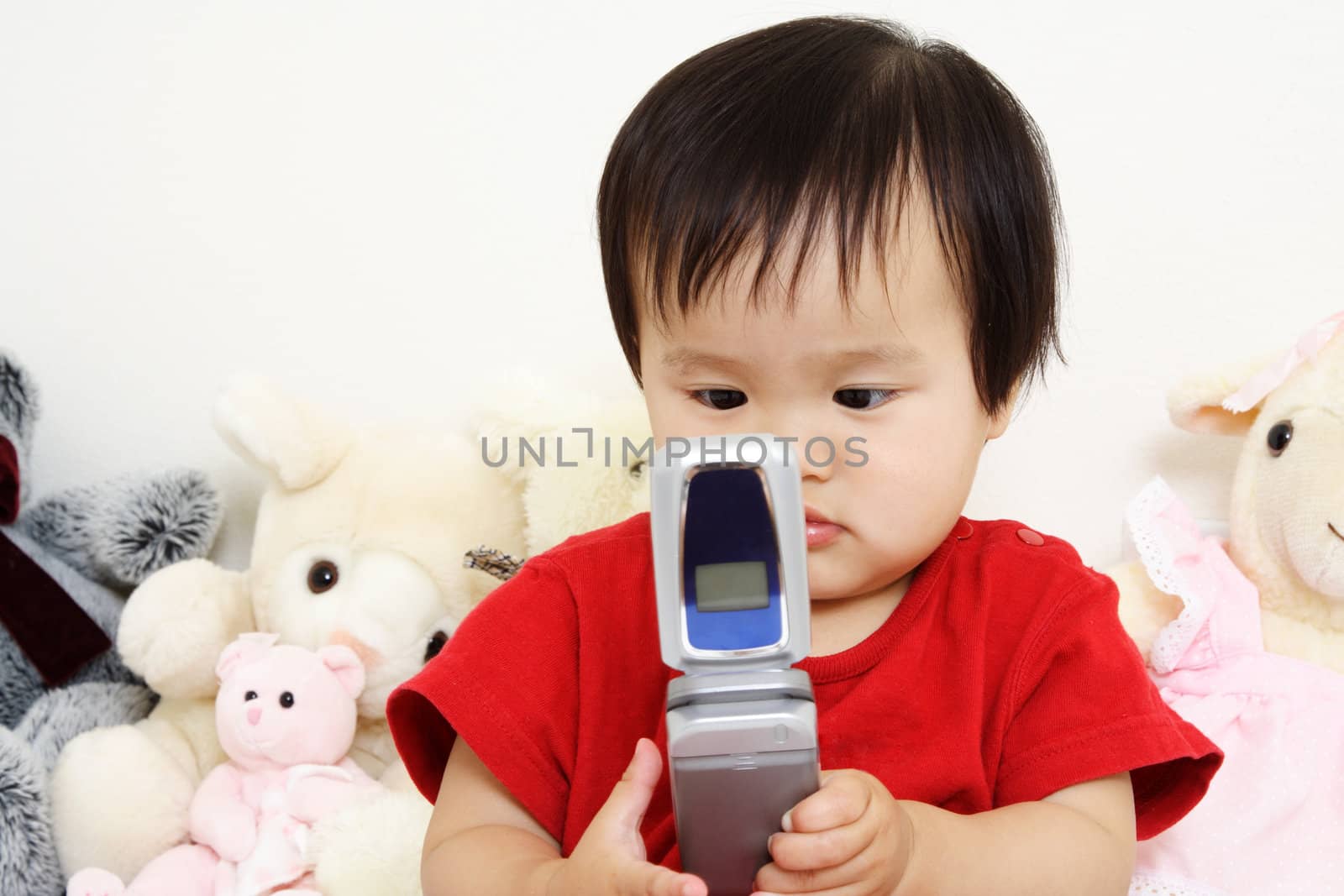 A cute little baby girl playing with a cell phone