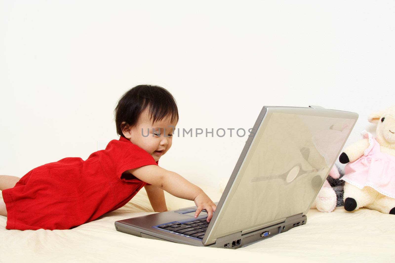 A cute baby girl playing with a laptop