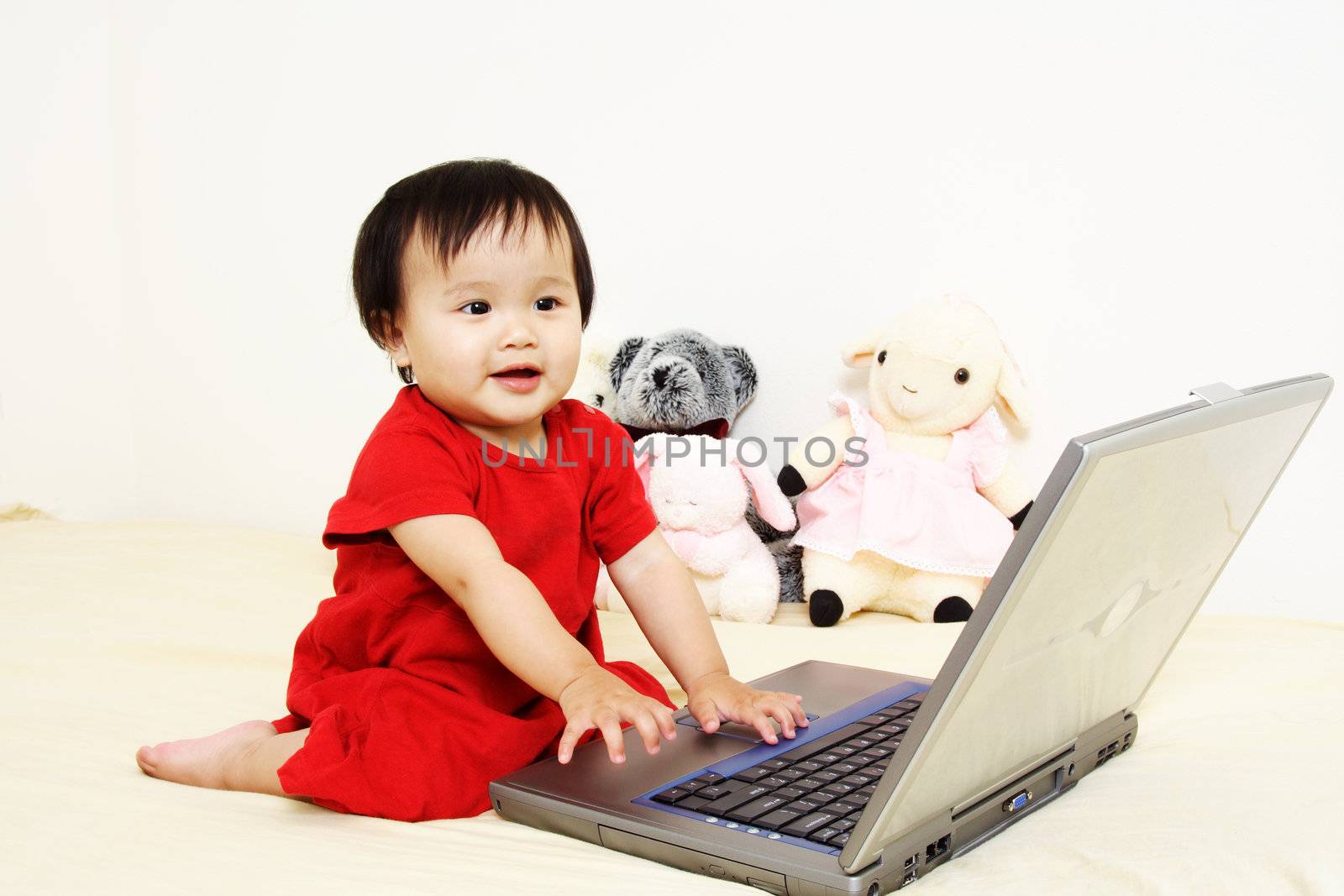 A cute little baby girl playing with a laptop