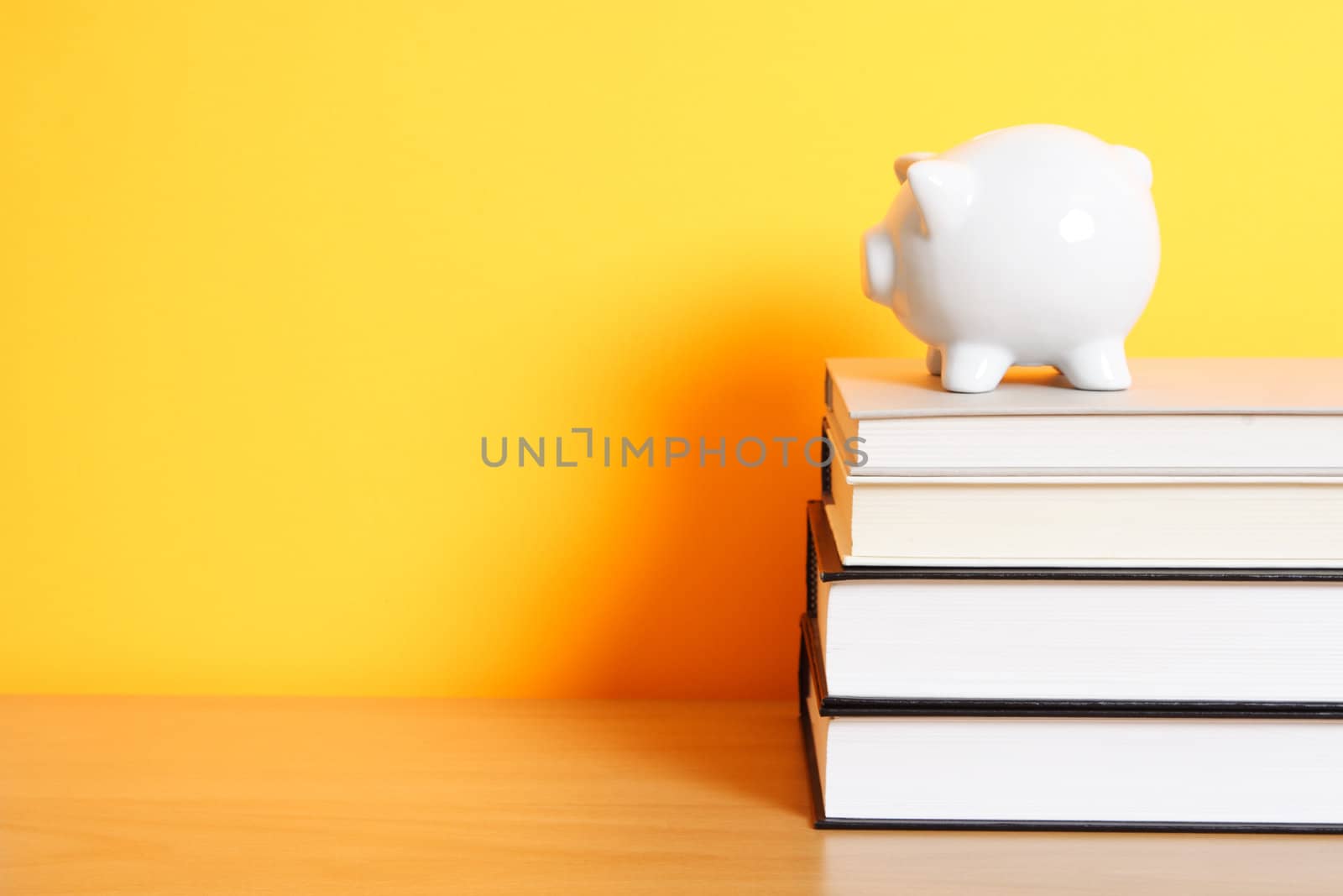 A piggy bank on top of a stack of books, good for saving for college theme