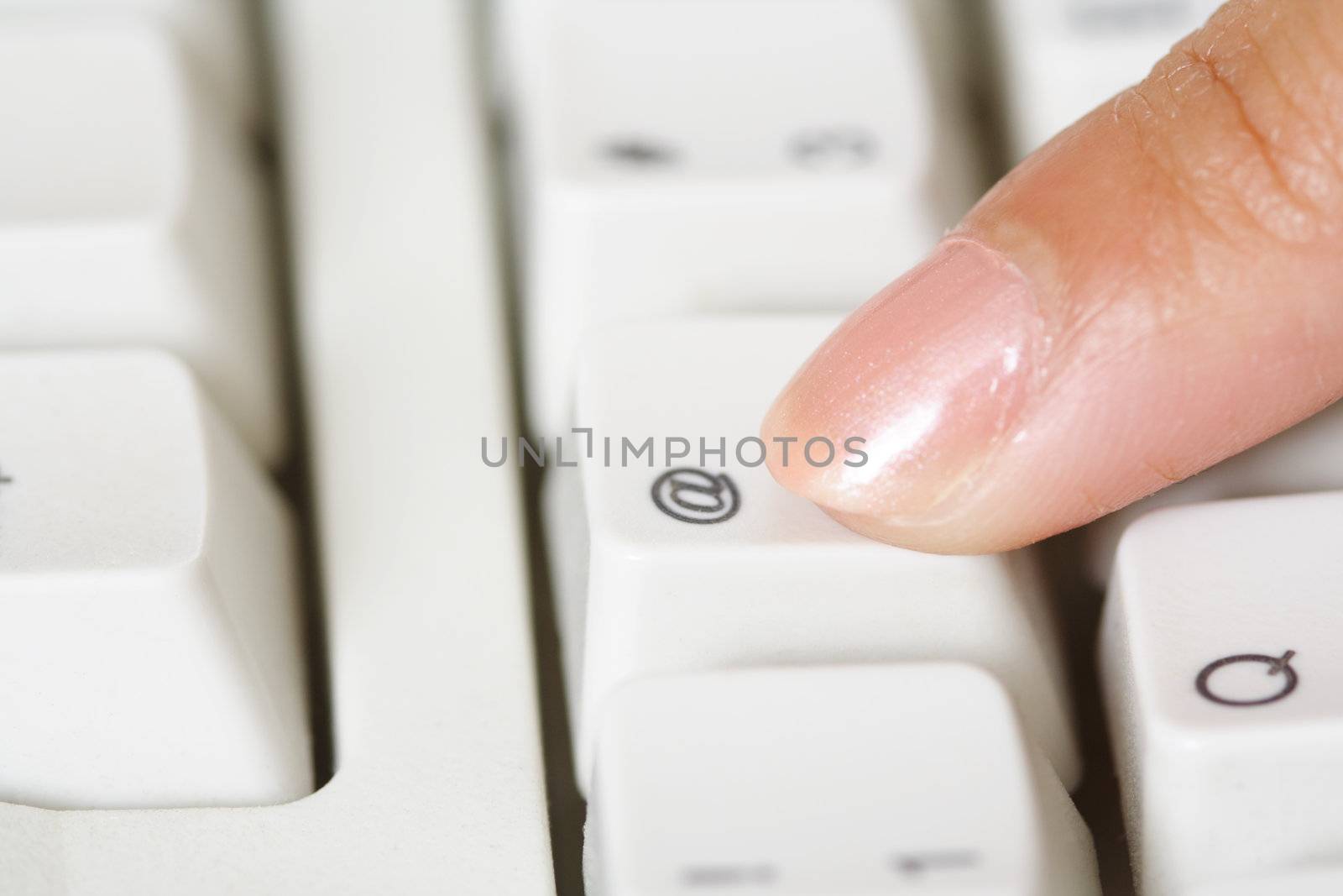 A close up of finger pressing the @ button