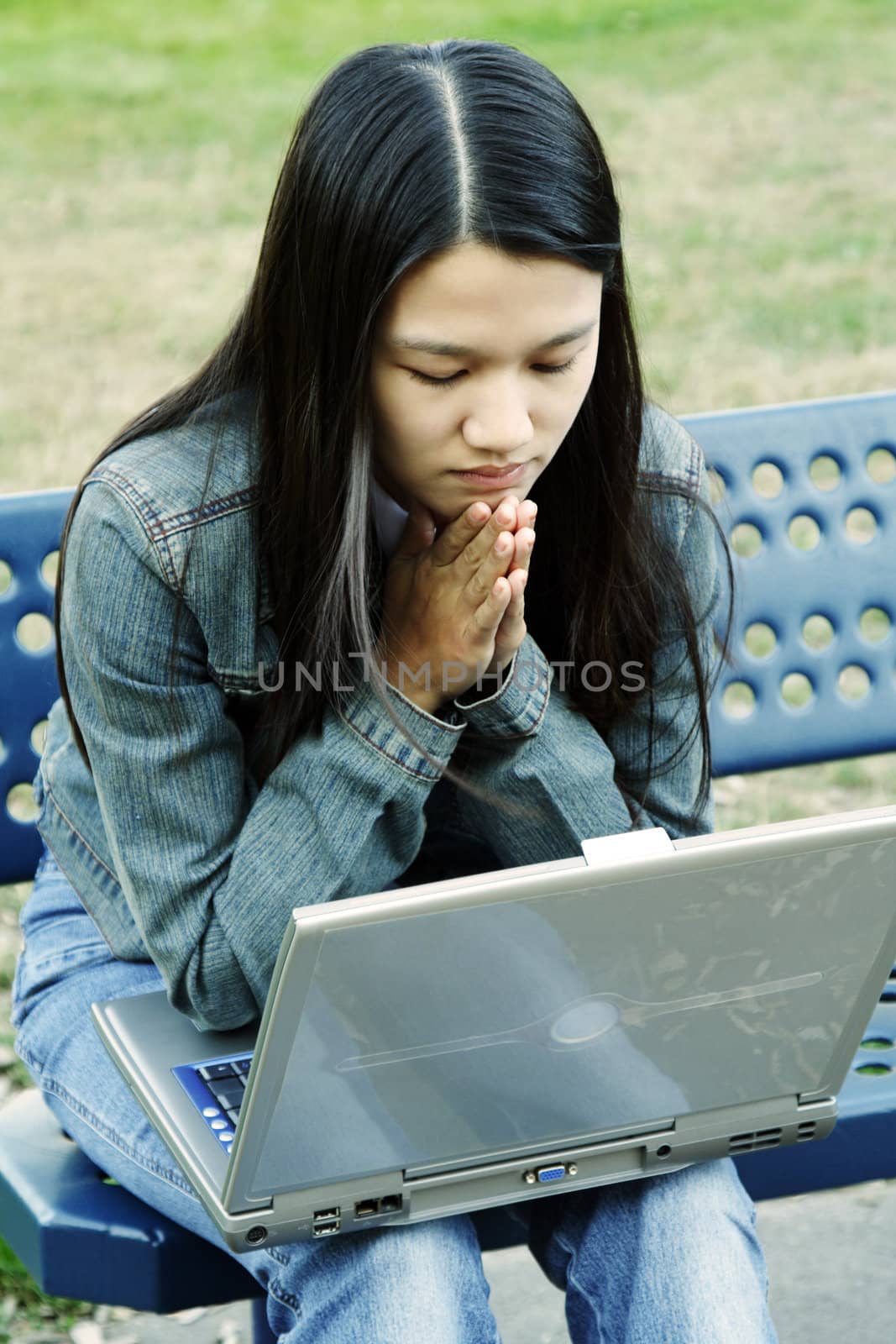 A girl sitting on a bench working on her laptop