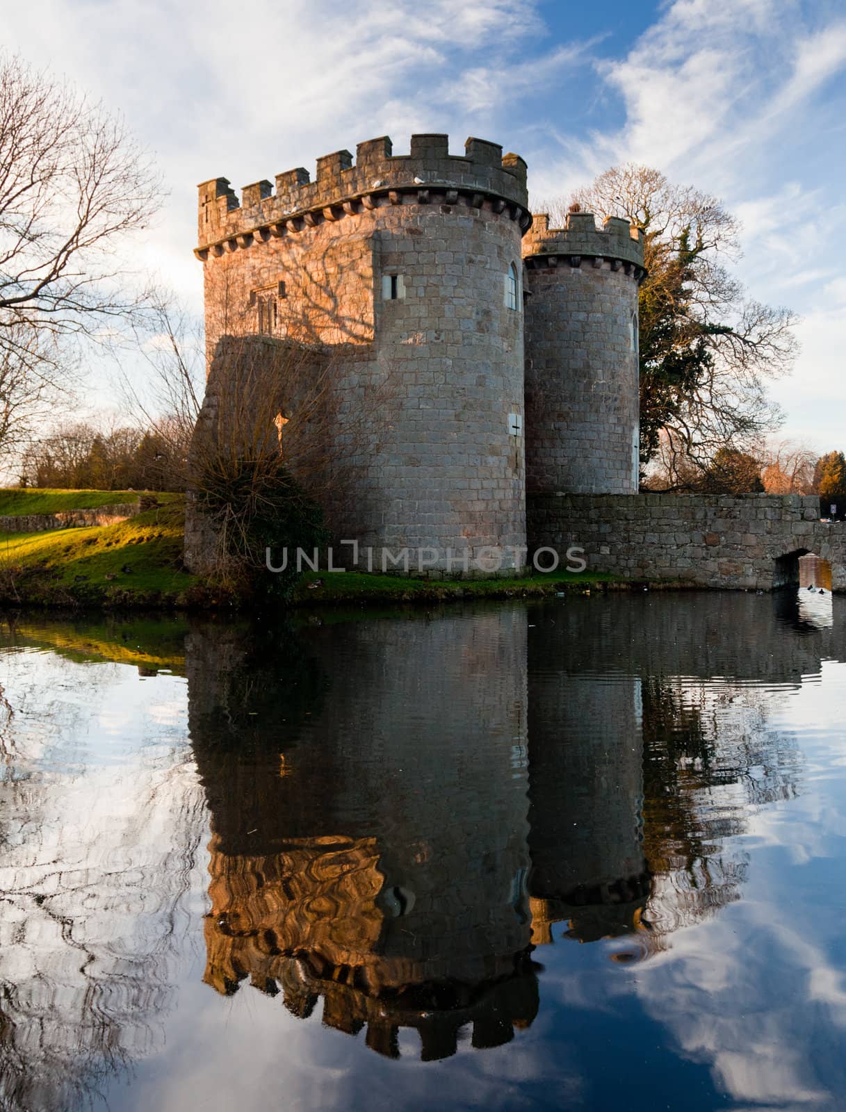 Ancient Whittington Castle in Shropshire, England reflecting in a calm moat round the stone buildings