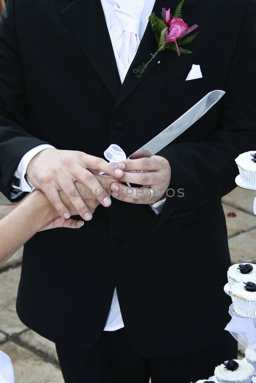 Bridal couple outdoors holding cake knife together