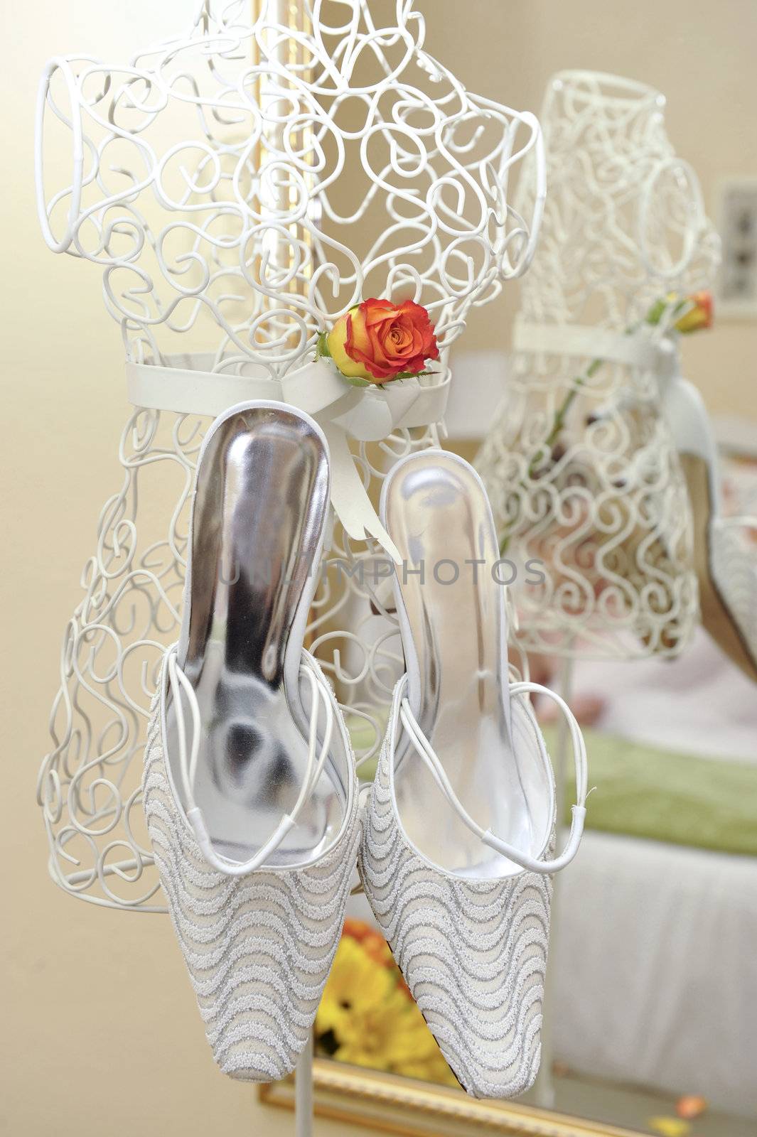 white wedding shoes hanging in front of a mirror on white frame