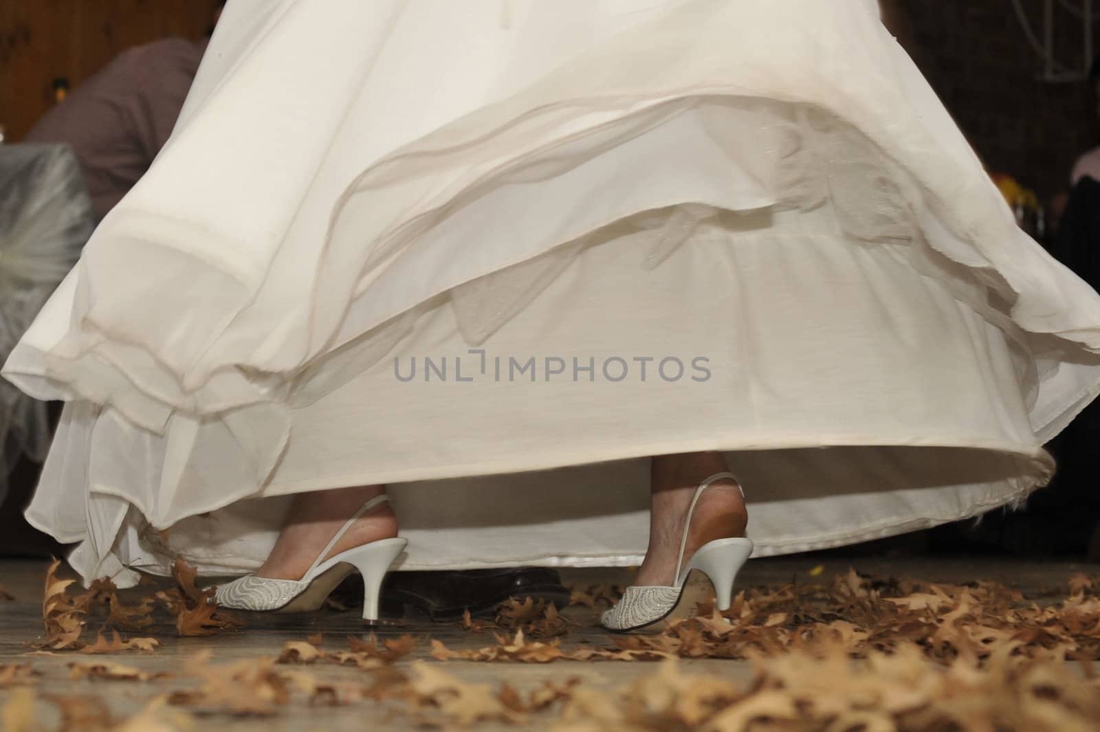 Bride walking on dead autumn leaves with shoes exposed