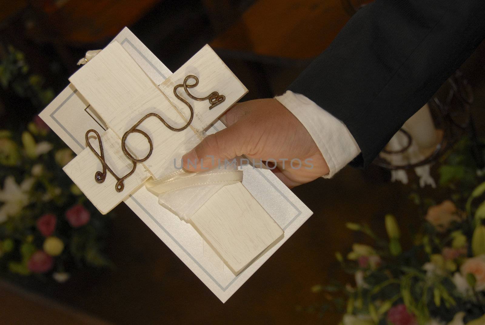 Groom holding crucifix with word love on
