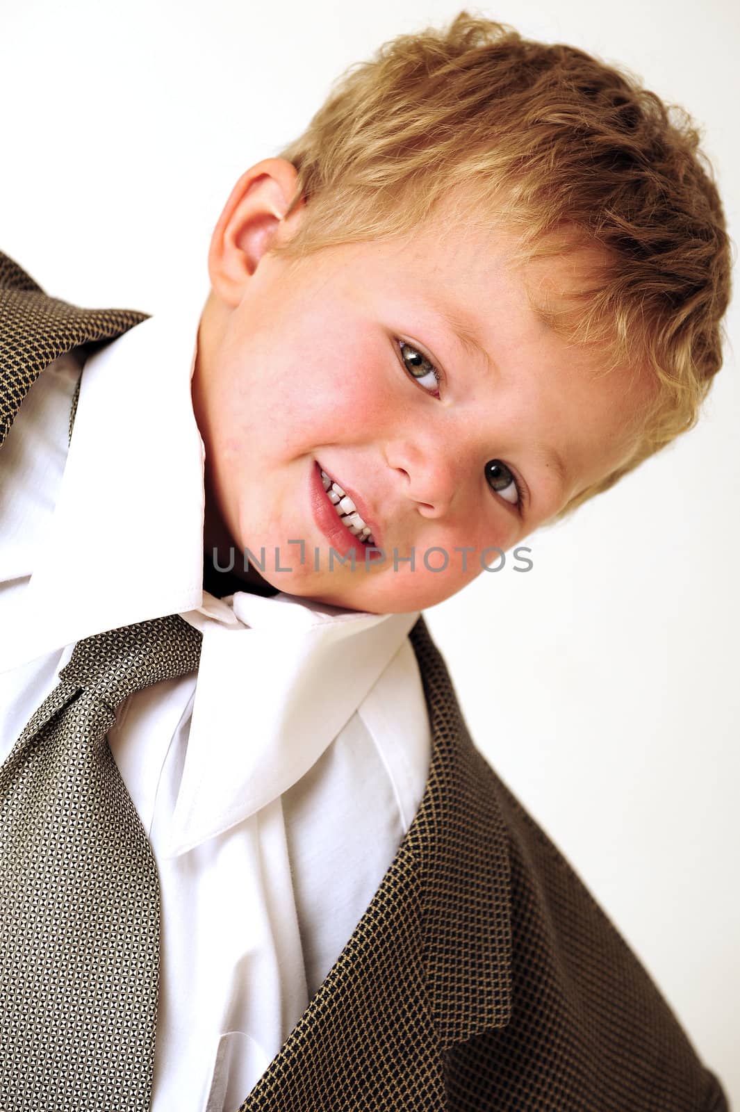 Blond young boy in oversized business clothes smiling