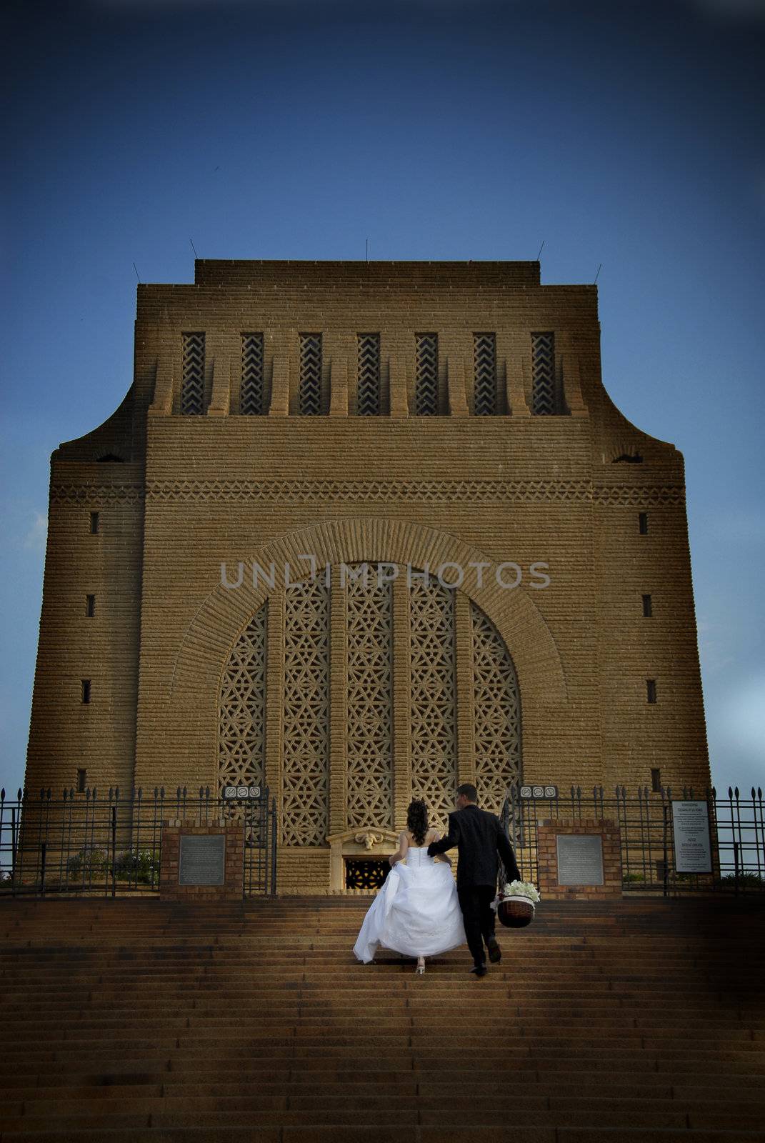 Bridal couple walking up big building stairs