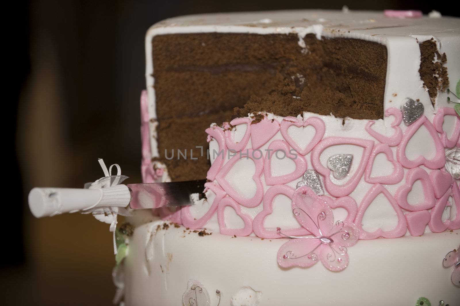 Knife in cut wedding cake with pink hearts