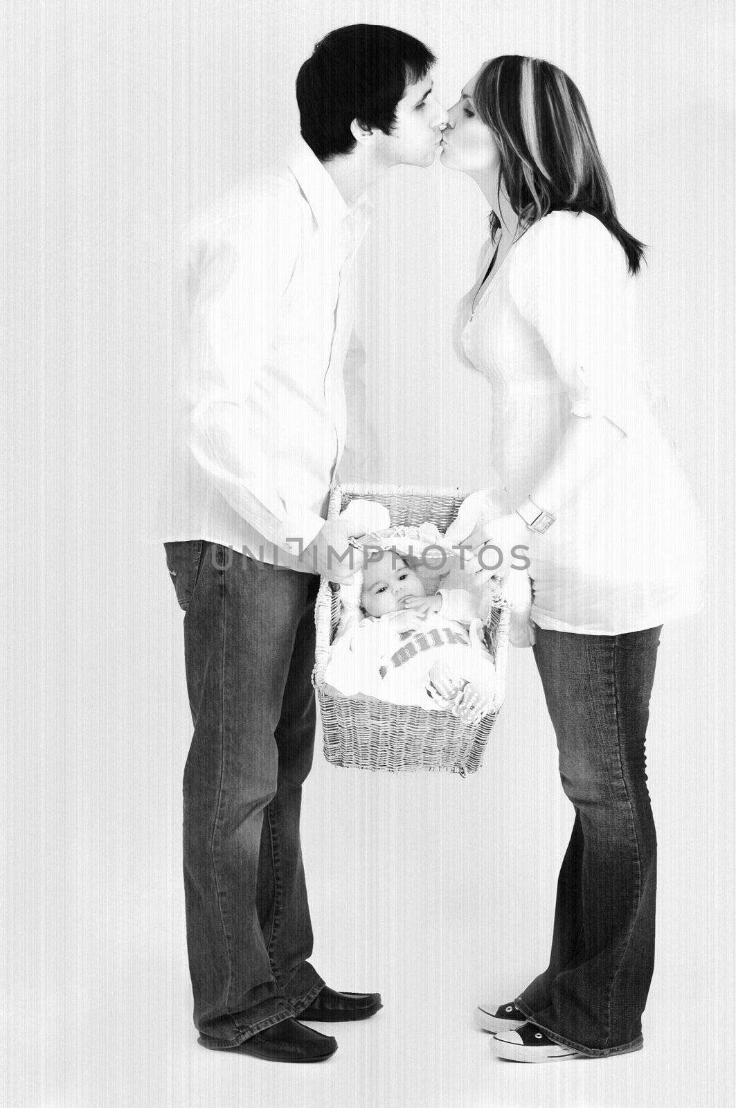 couple holding new baby in basket and kissing