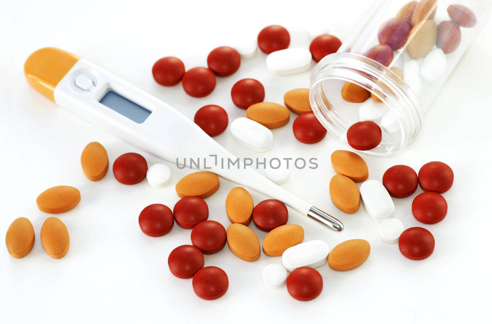 Health background: digital thermometer with many colorful spilled pills with open plastic bottle.