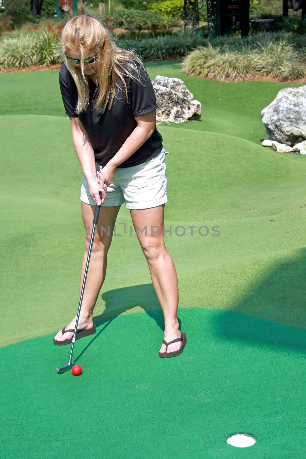 A woman ready to putt her golf ball