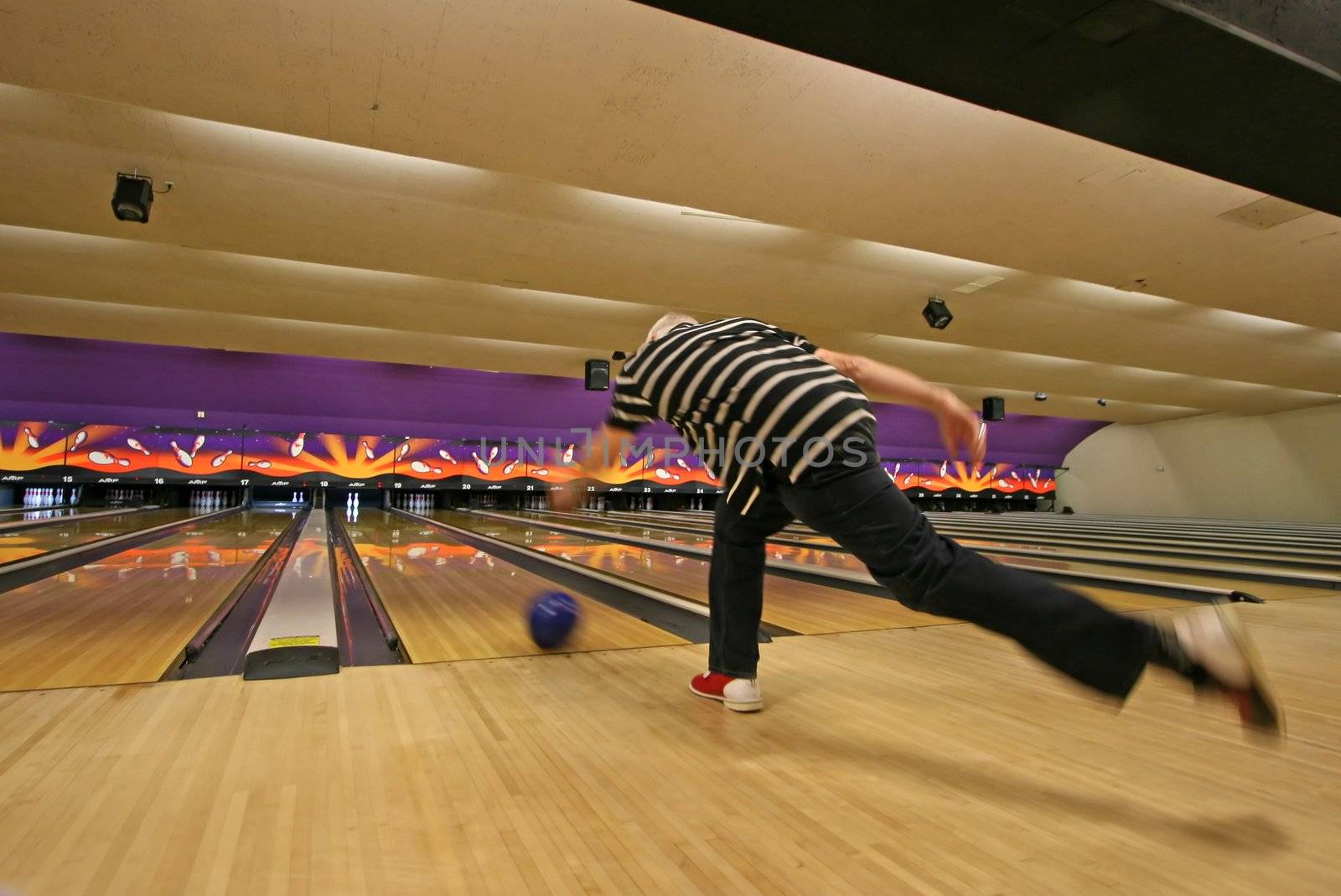 A man who has just thrown his bowling ball