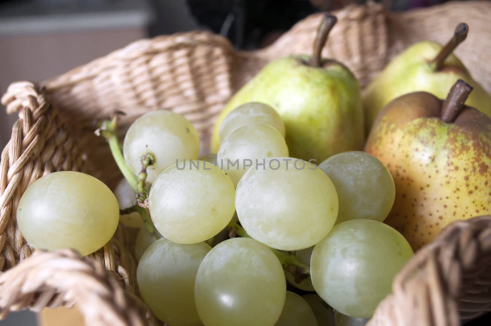 Green yellow grapes in a basket with pears