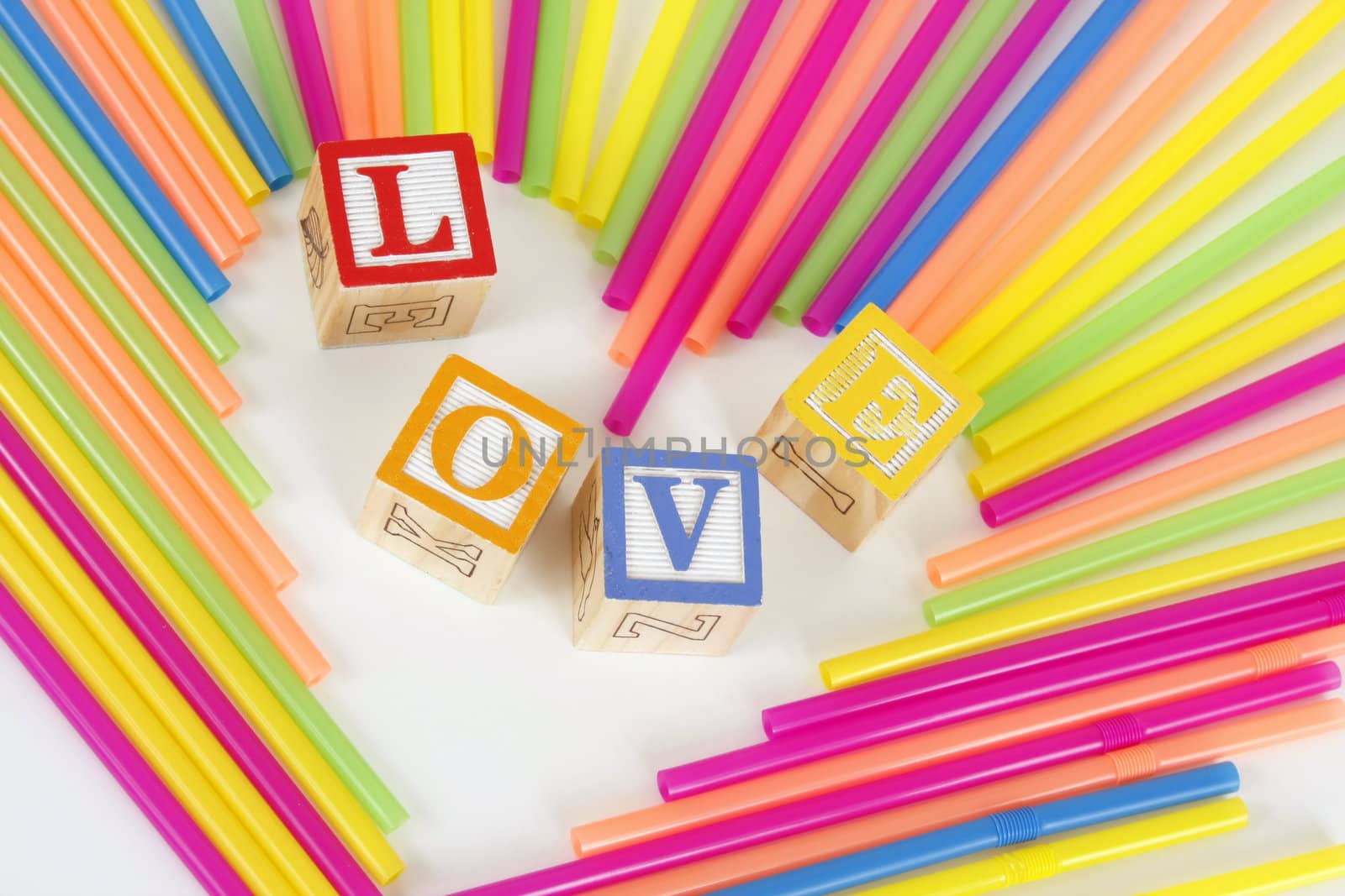 Colorful Straws make a heart shape and childrens bloks spell the word Love.