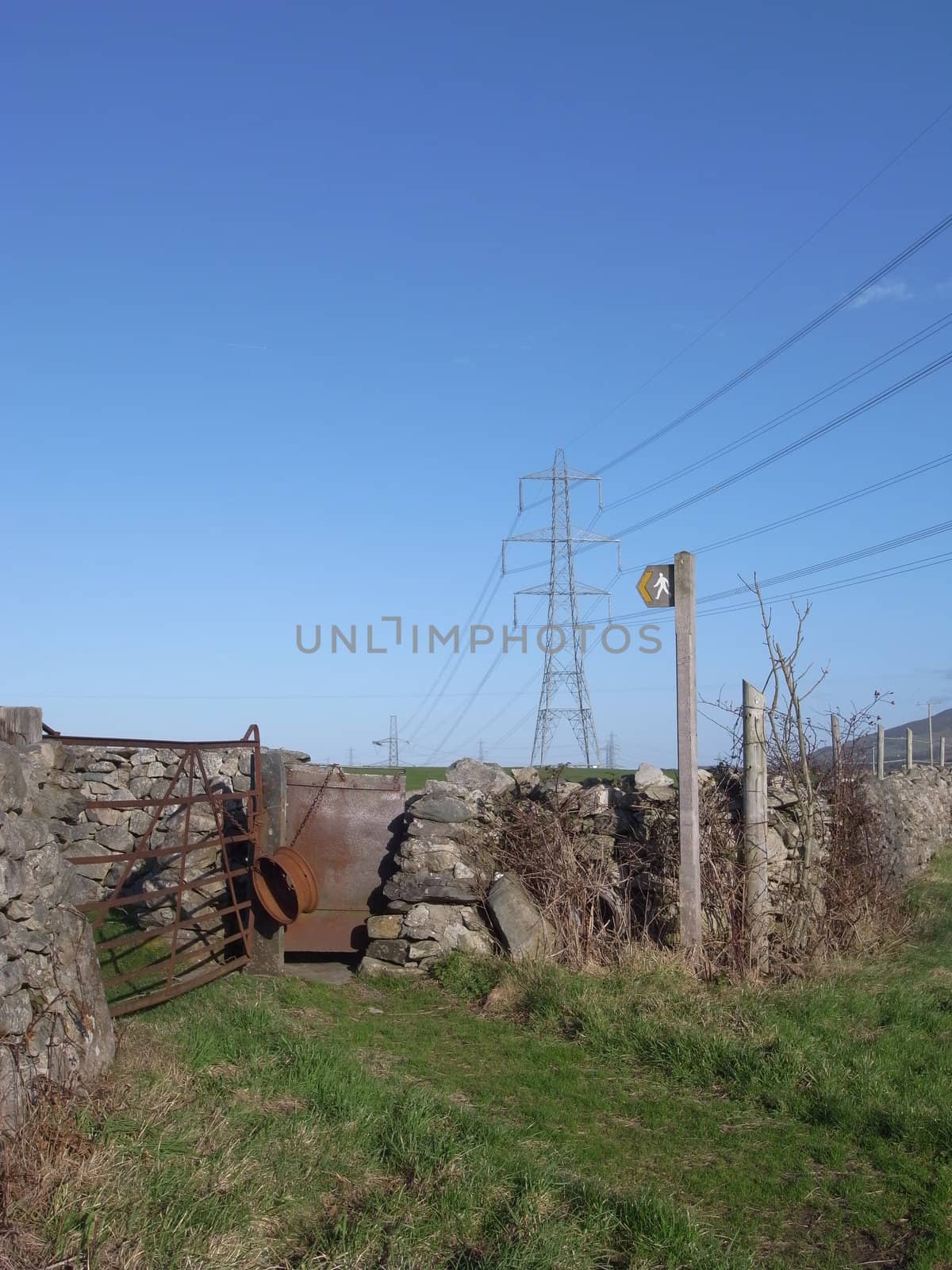 A footpath leads to a pair of gates with a sign pointing out the public access area.